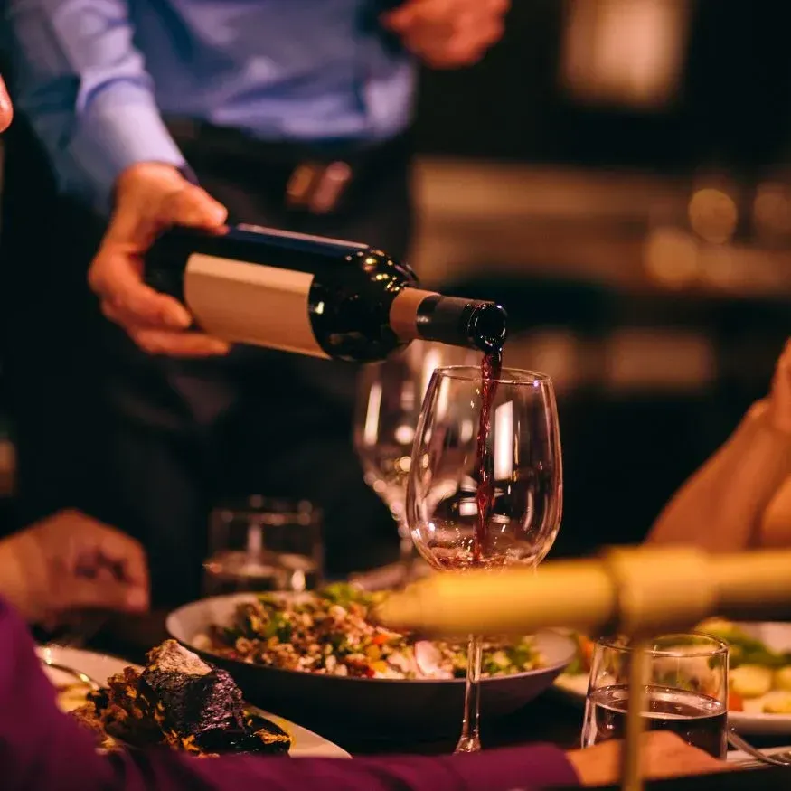 A man pouring a bottle of wine into a glass