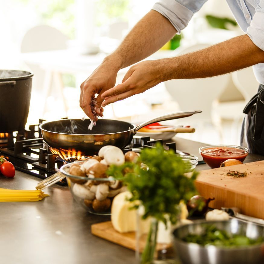 A man is preparing food on a stove in a kitchen