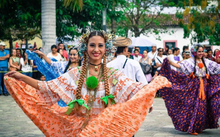 A woman in a traditional dress is dancing in front of a crowd.