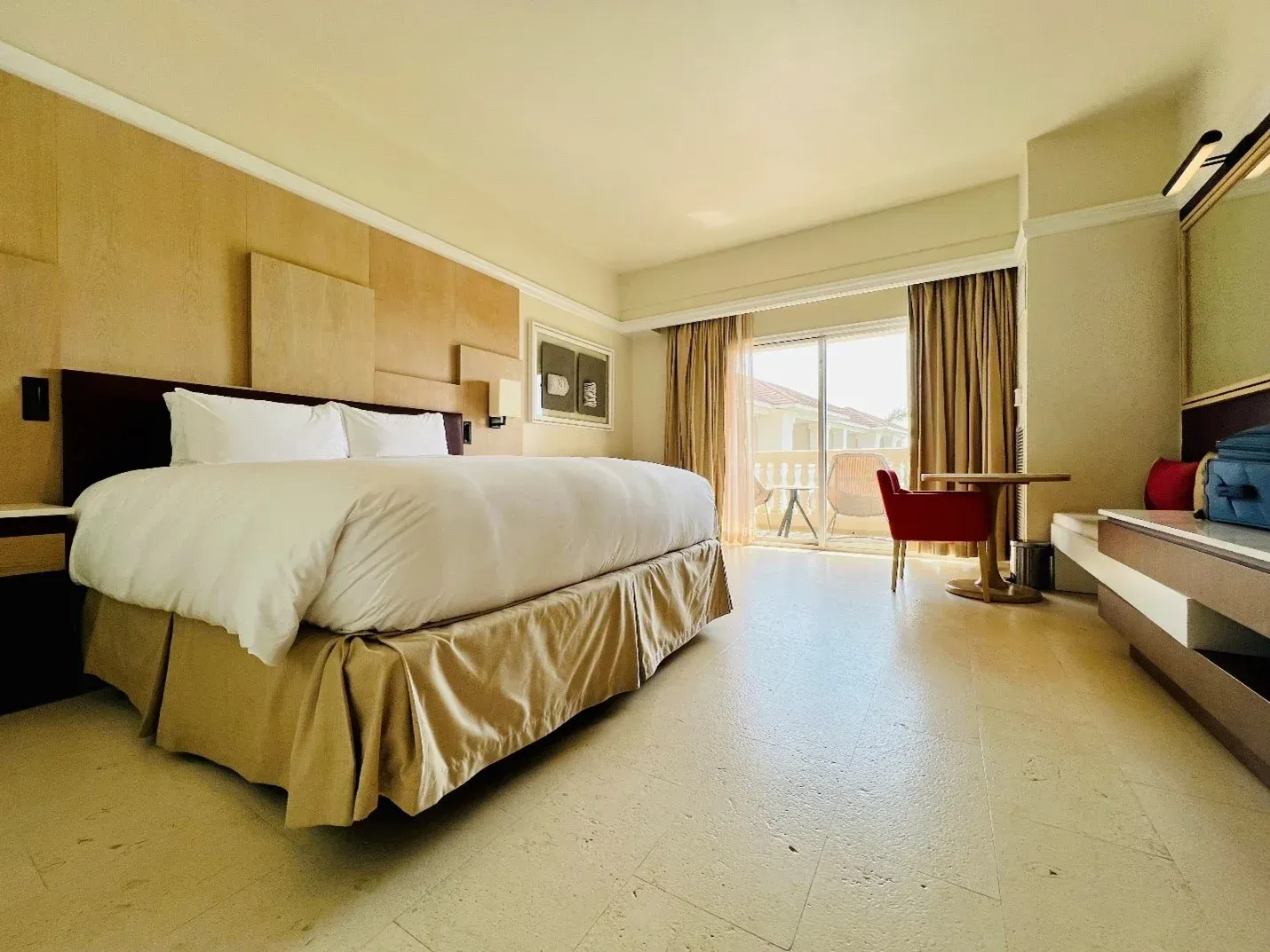 A hotel room with a king size bed , table and chairs.