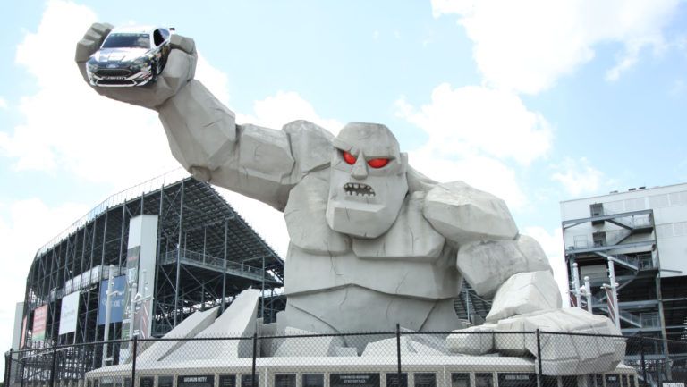 A statue of a monster holding a car in his hand