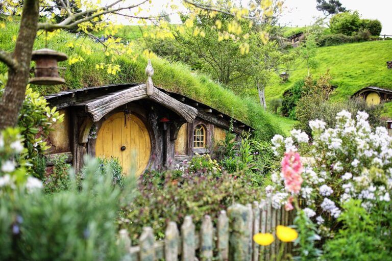 A small house sitting on top of a hill surrounded by flowers and trees.