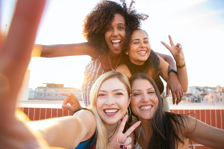 A group of women are taking a selfie together on a rooftop.