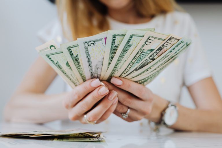 A woman is holding a fan of money in her hands.