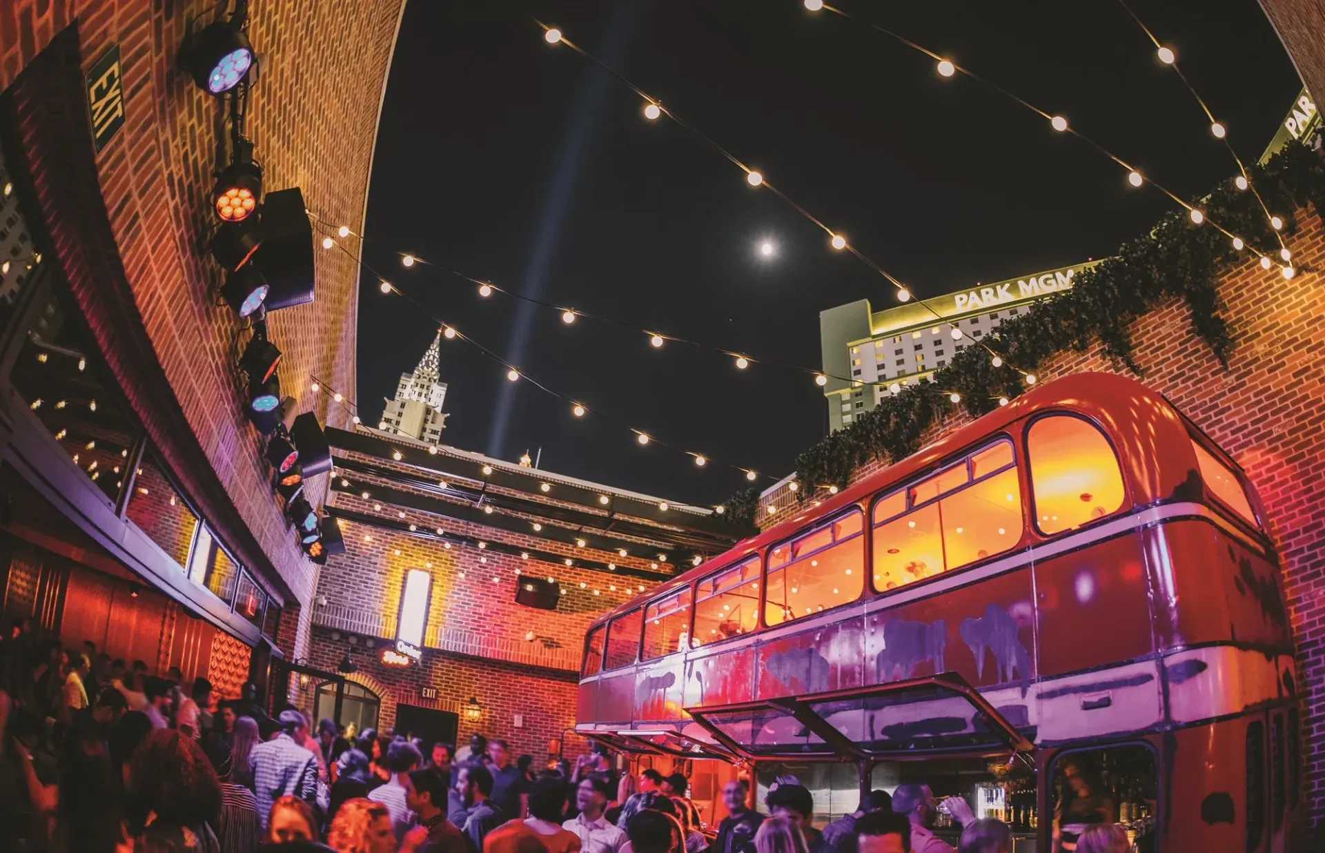 A double decker bus is parked in front of a crowd of people at night.