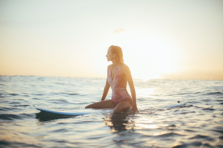 A woman is sitting on a surfboard in the ocean.