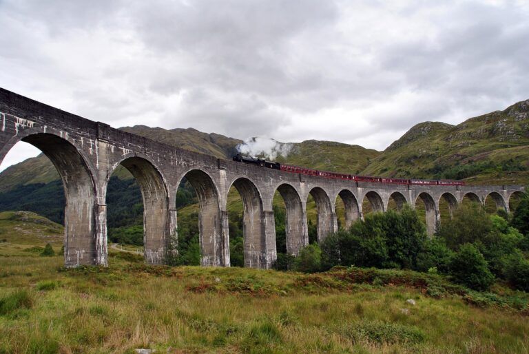 A train is going over a bridge in the mountains.