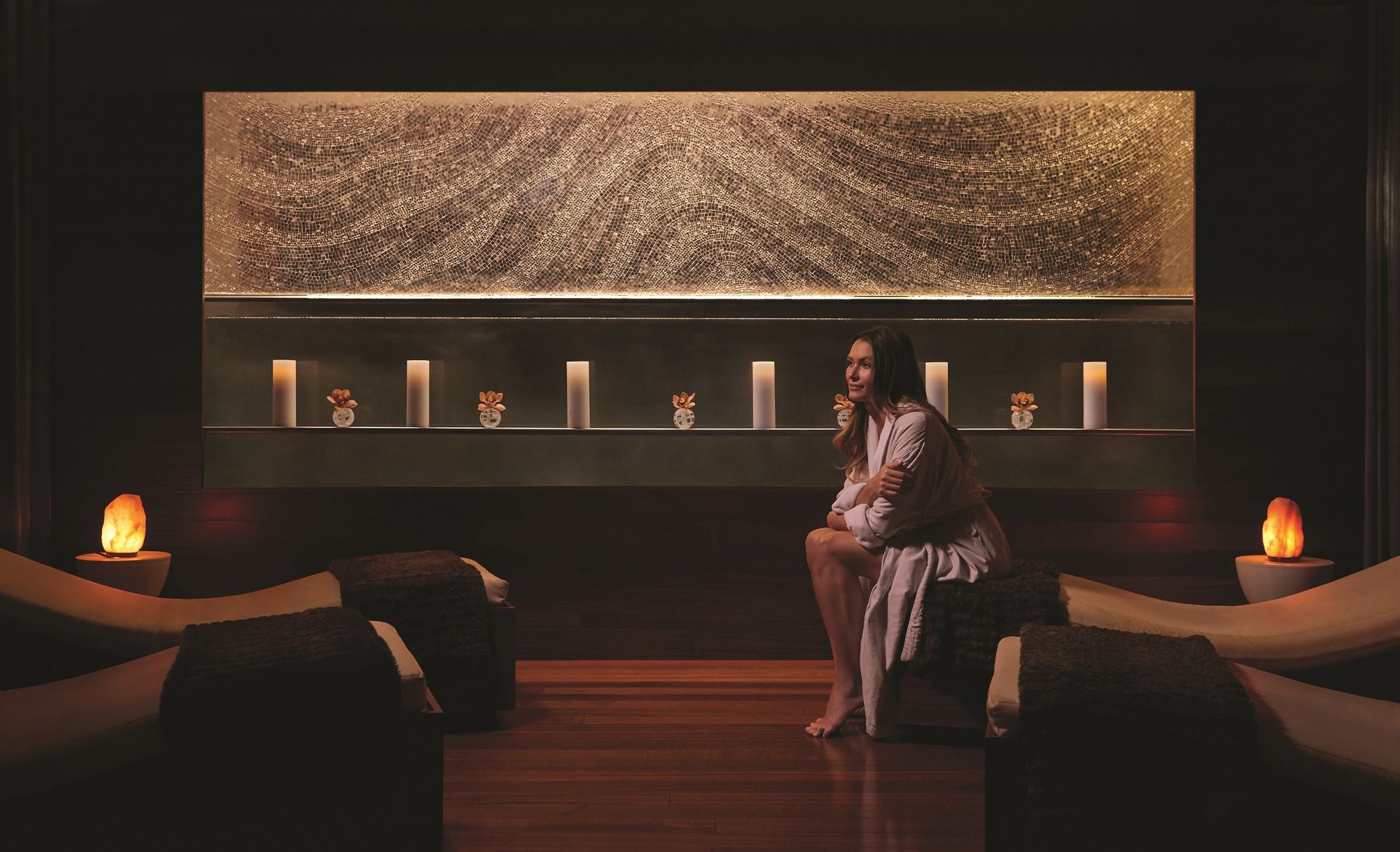 A woman is sitting on a chair in a room with candles.