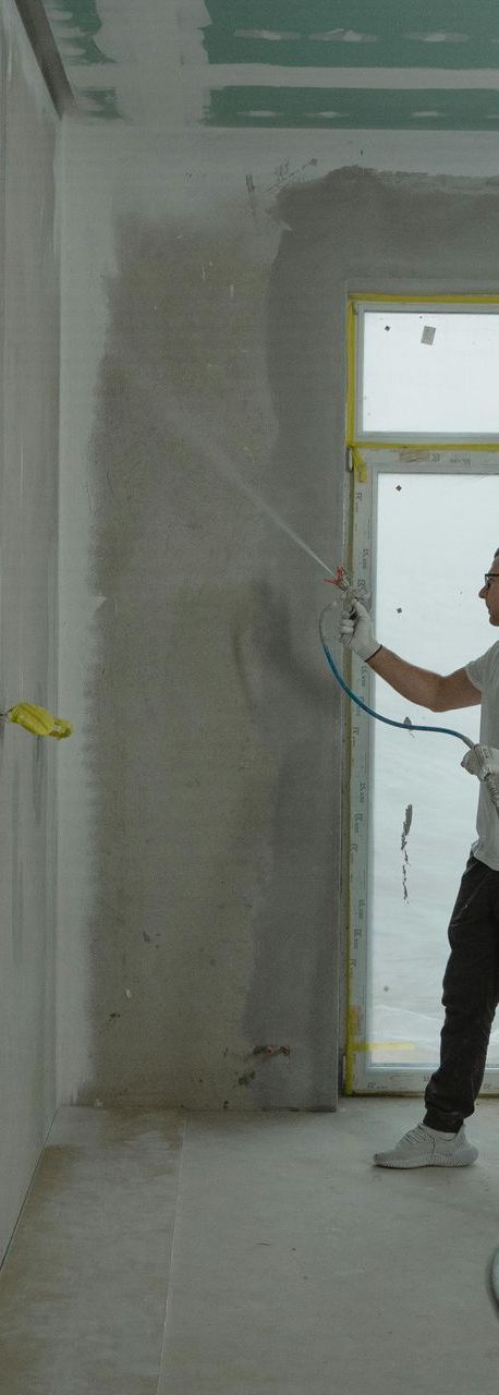 A man is spraying paint on a wall in a room.