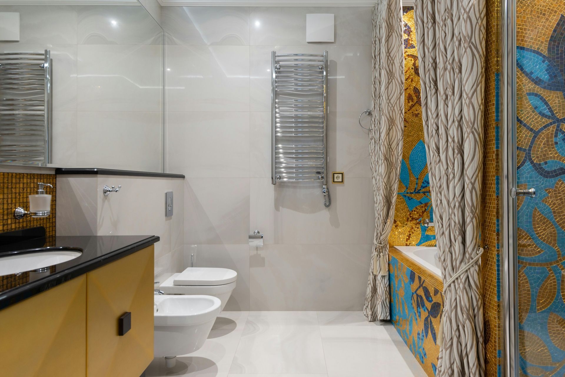 A bathroom with two toilets , a sink , and a shower curtain.