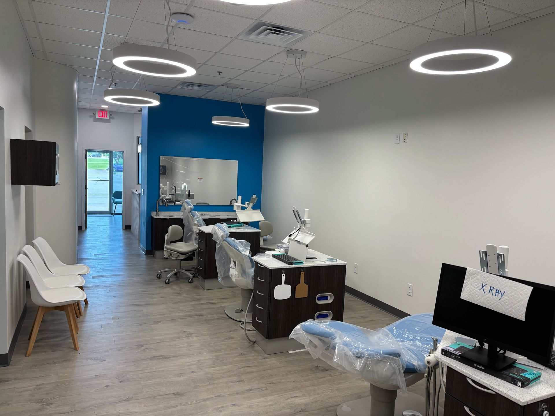Pharmacy counter with dark wood panels, a clear sign, and waiting chairs.