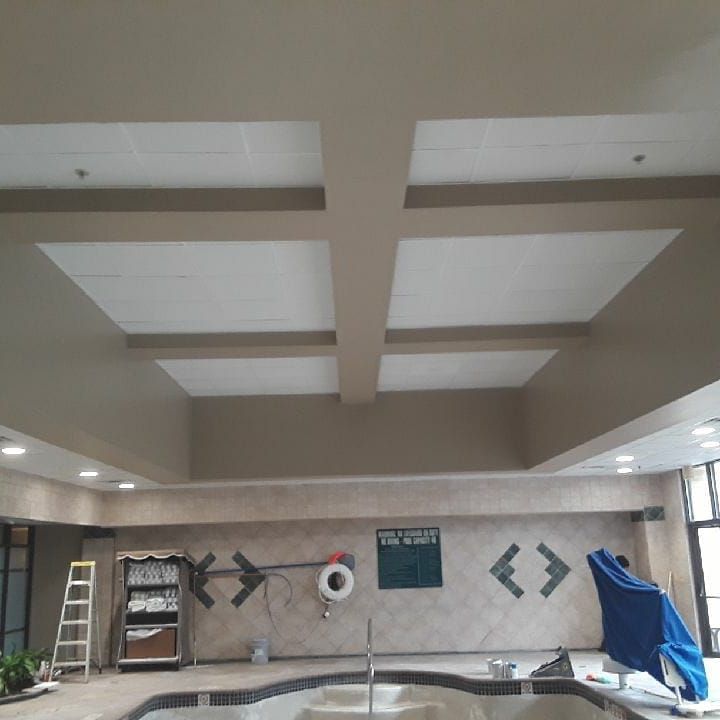 Indoor swimming pool with beige walls, recessed ceiling, and safety equipment.