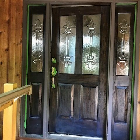 Dark stained wooden front door with glass panels and sidelights.