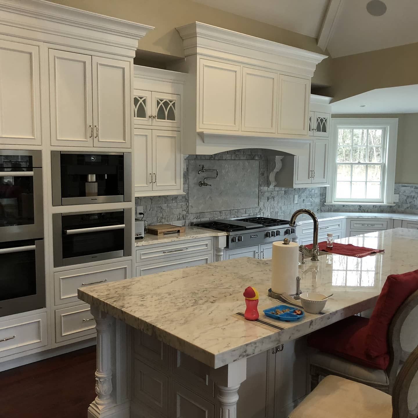 White kitchen with granite island, stainless steel appliances, and white cabinetry.