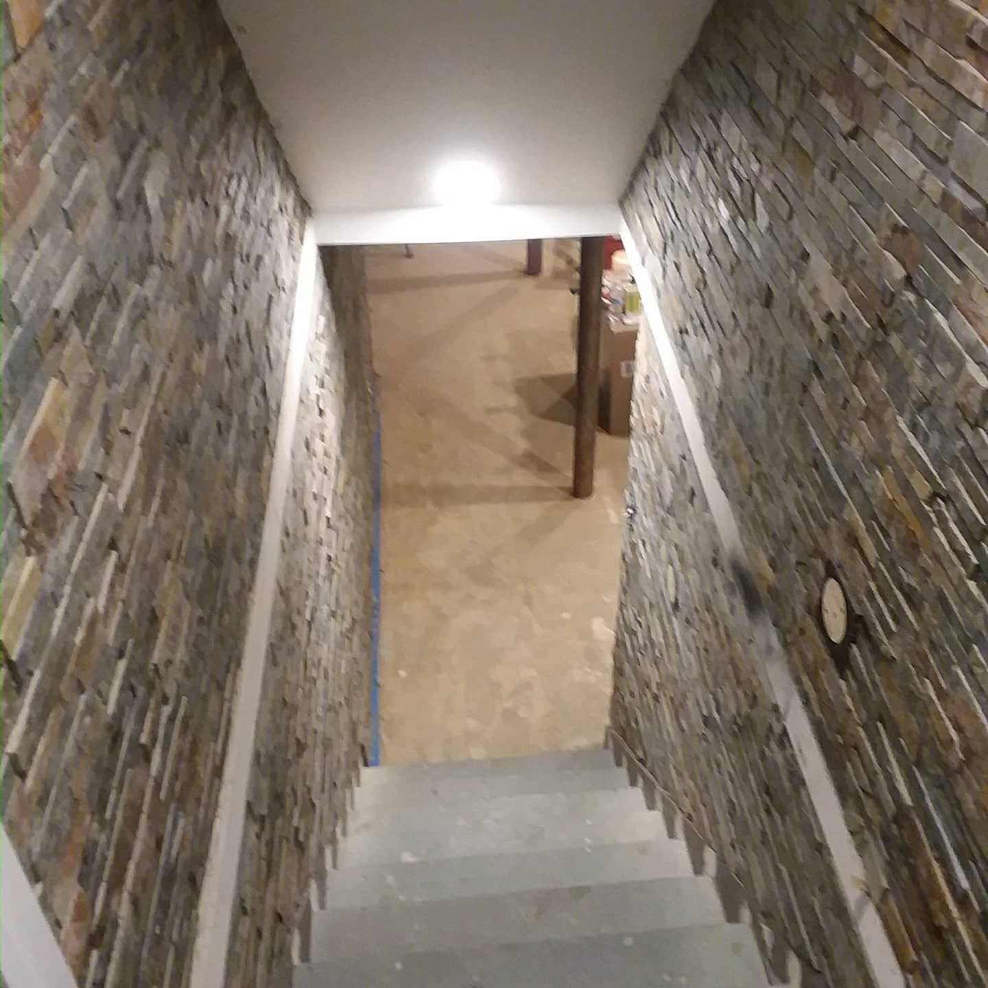 Stairwell with stone walls and a doorway at the top, leading into a basement.