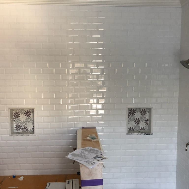 White subway tile shower with two built-in niches with floral tile.