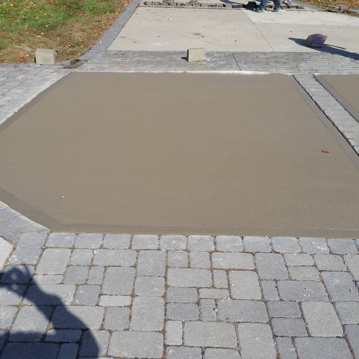 Fresh concrete poured within a brick border. Construction site, outdoor, sunny.