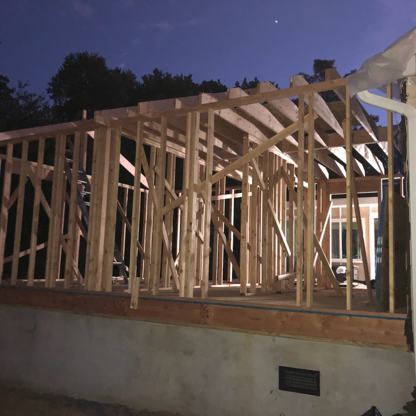 Wood frame of a building under construction, exterior view at dusk.