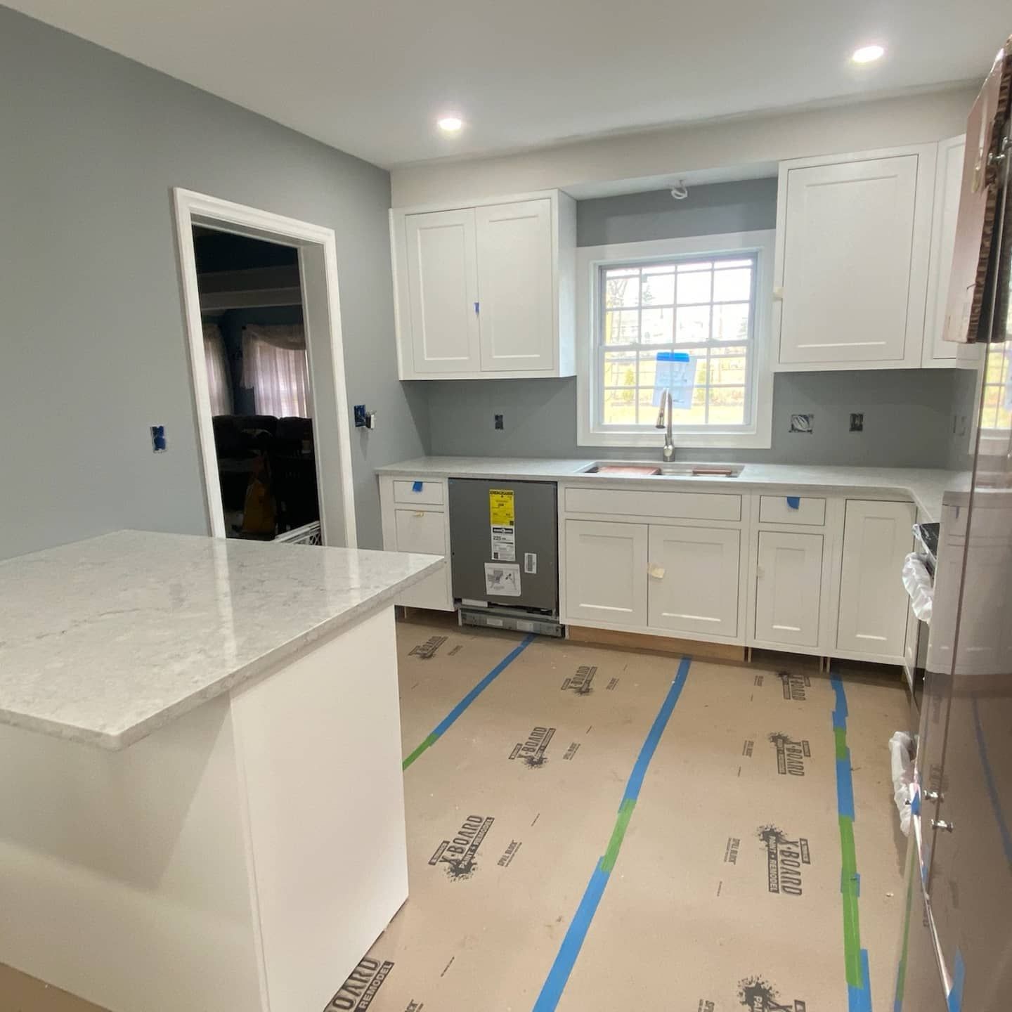 Newly renovated kitchen with white cabinets, gray walls, island and flooring papered.