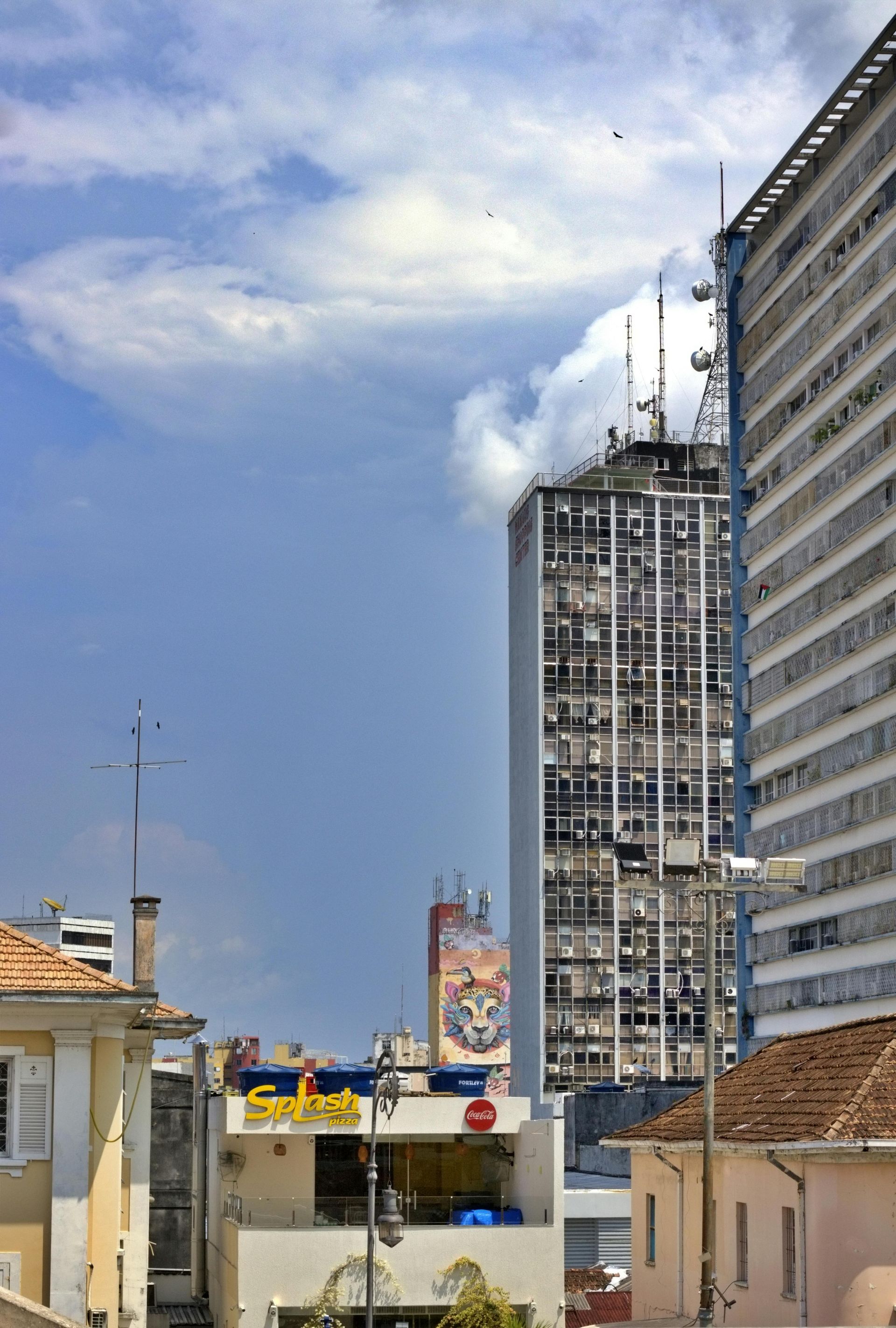 City buildings against a cloudy blue sky. Includes a restaurant sign and antennas.
