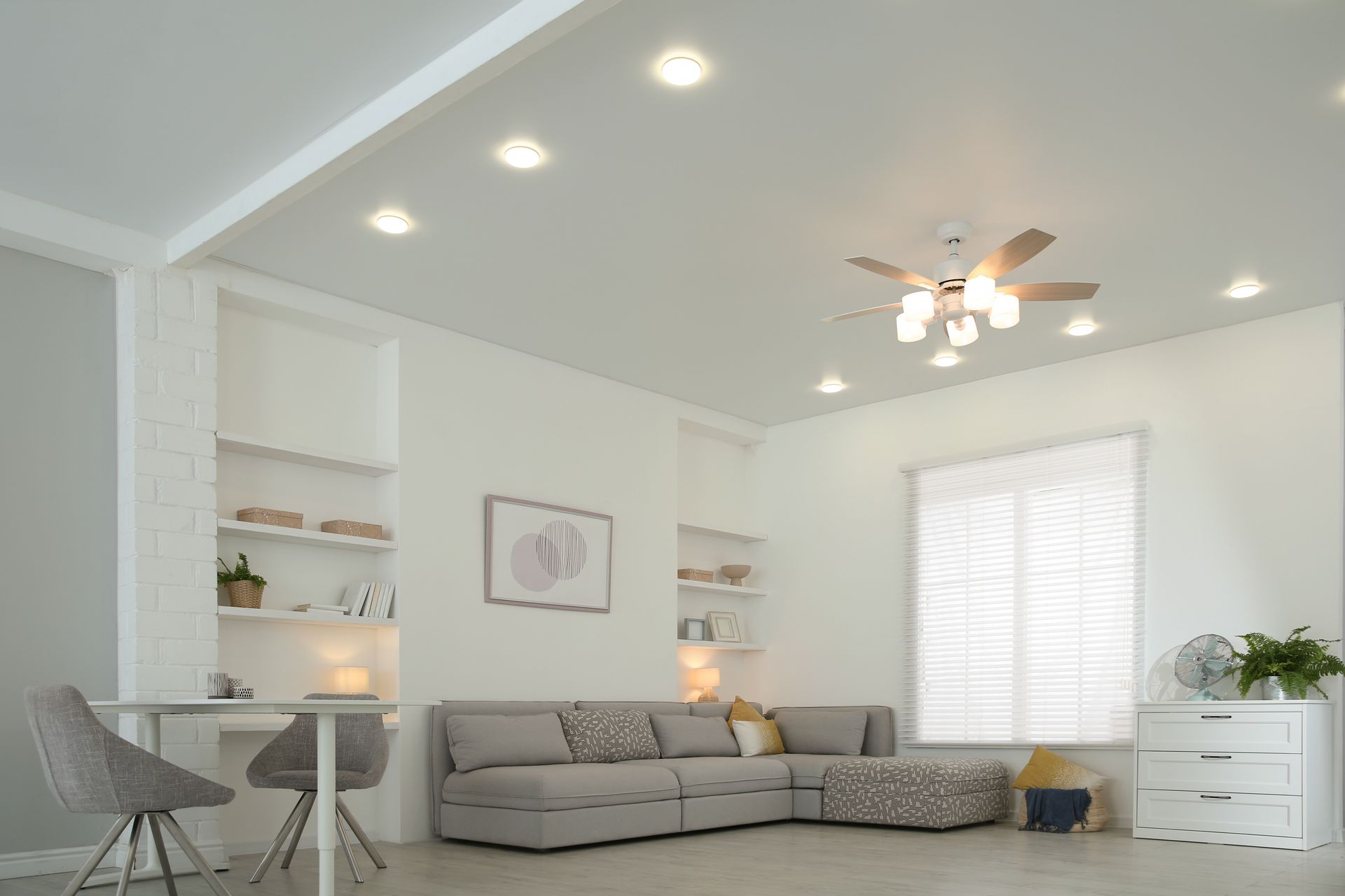 Bright, modern living room with gray sectional sofa, built-in shelves, and recessed lighting.