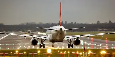 An airplane is taking off from an airport runway at night.