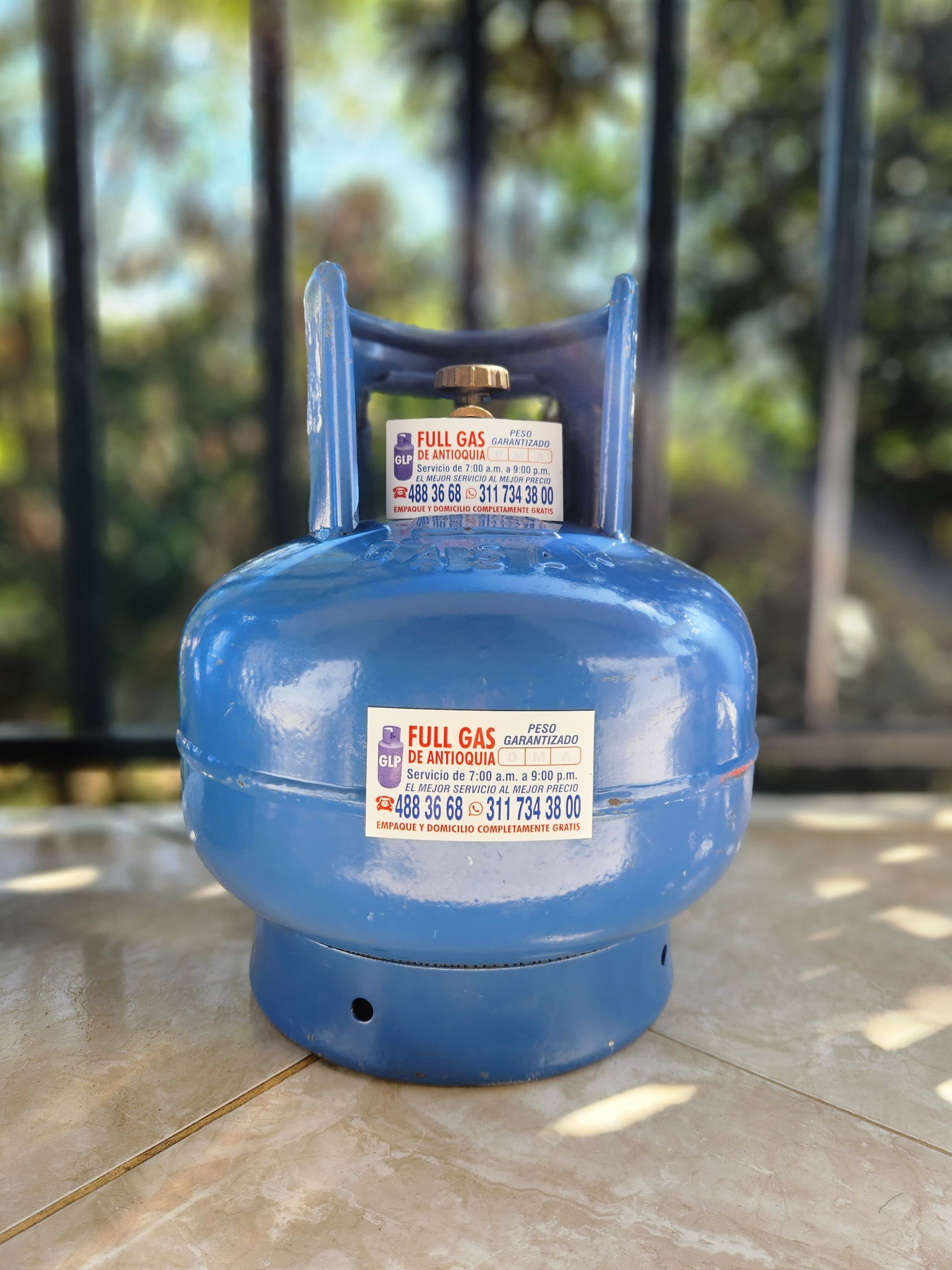 Un tanque de propano azul está sobre una superficie de concreto.