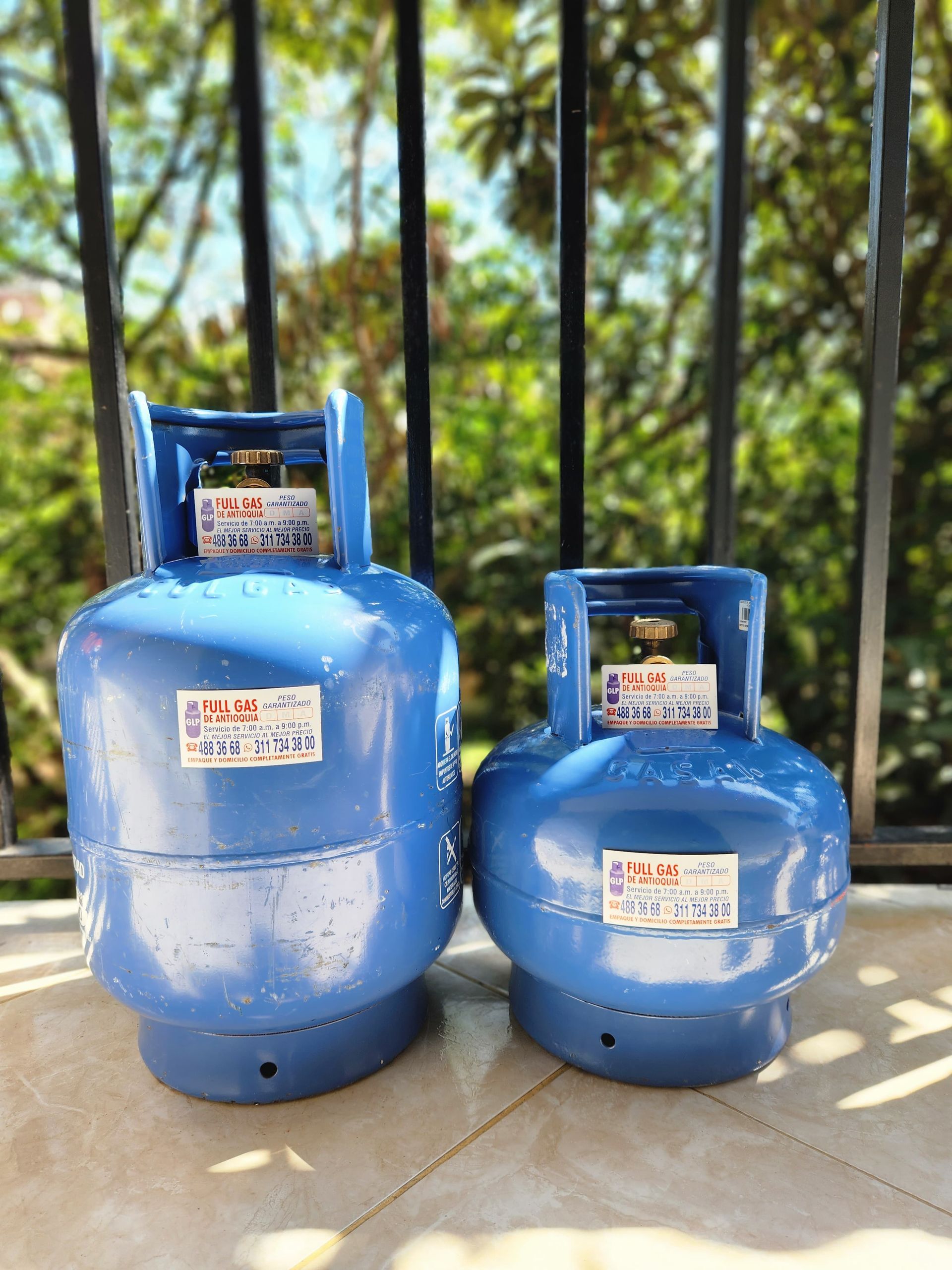 Dos bombonas de gas azules están una al lado de la otra en un balcón.