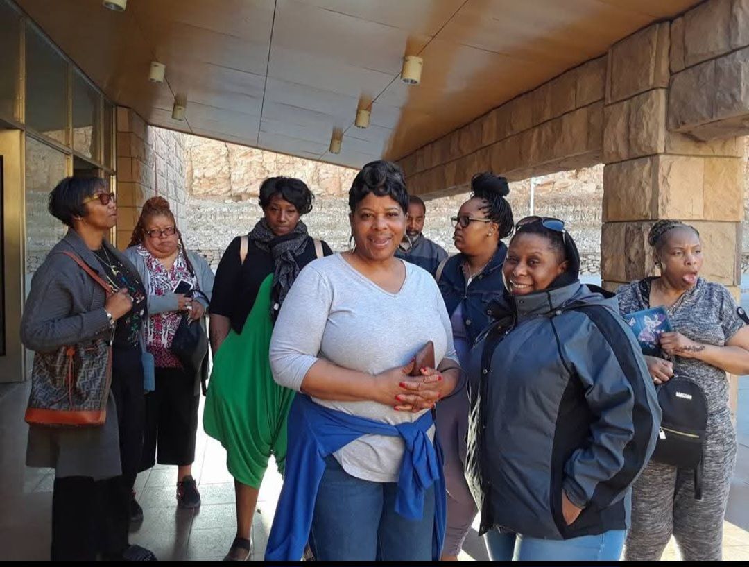 A group of women are posing for a picture in front of a building.