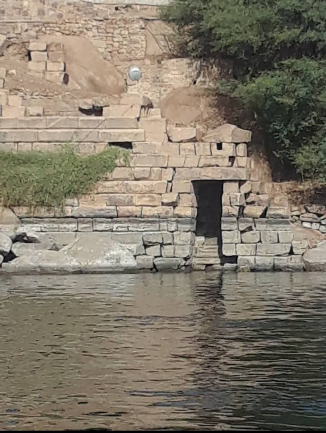 A stone wall surrounds a body of water with stairs leading up to it.