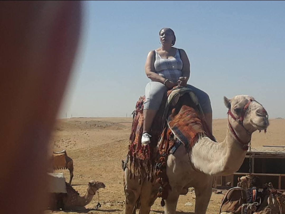 A woman is riding a camel in the desert