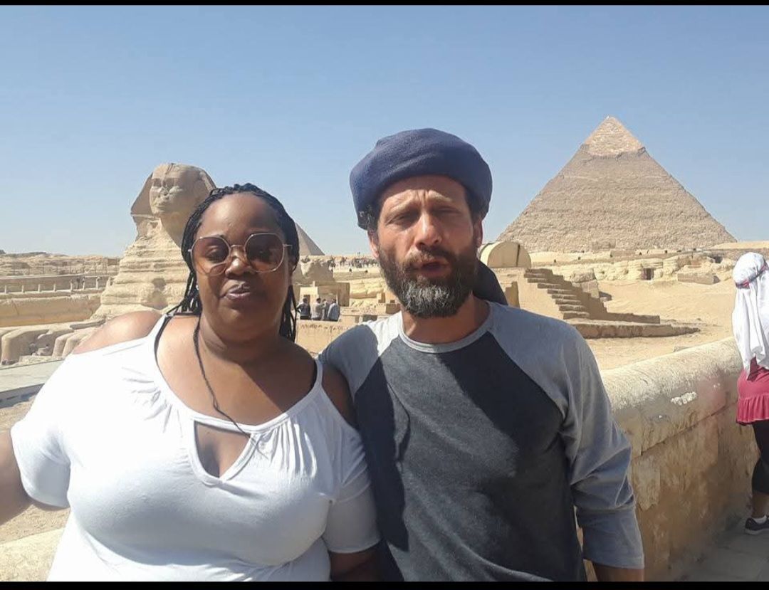 A man and a woman are posing for a picture in front of a pyramid