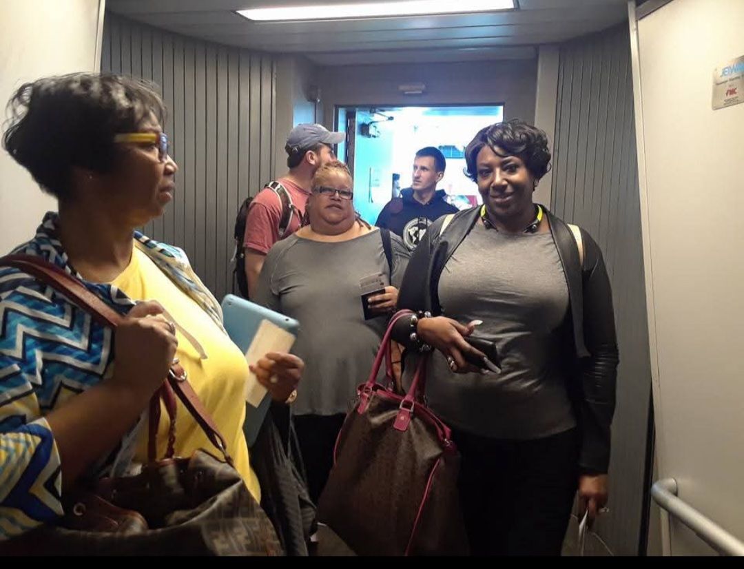 A group of people are standing in a hallway with a sign that says ' exit ' on it