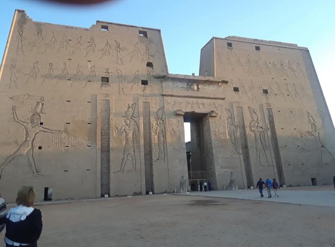 A woman stands in front of a large building