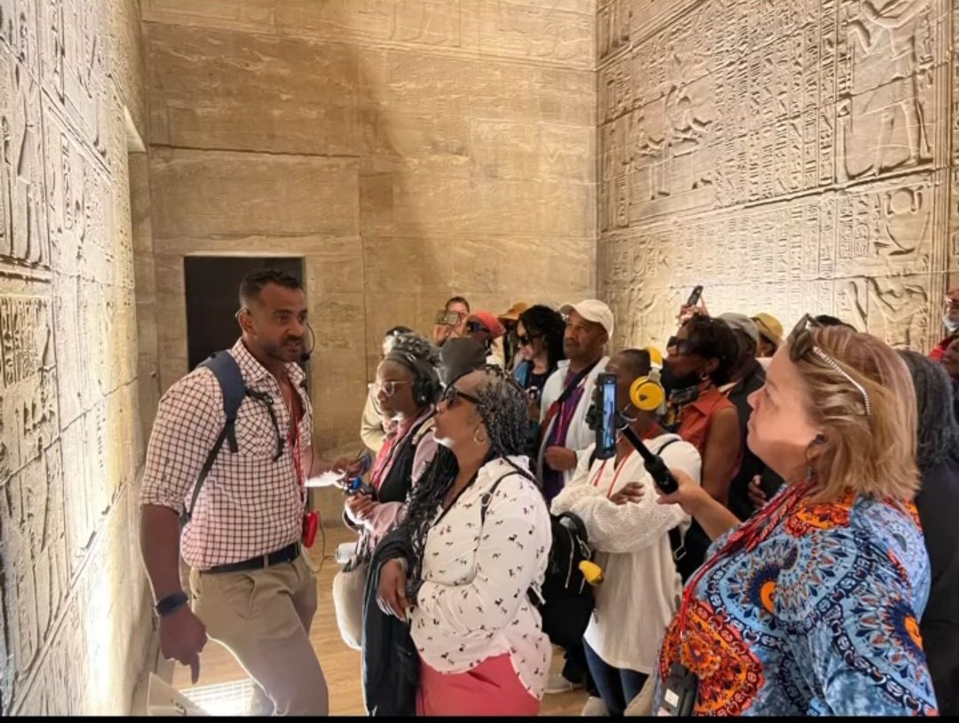 A group of people are standing in a room looking at a wall.