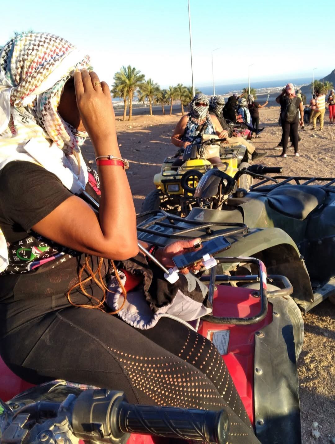 A woman wearing a head scarf sits on a four wheeler