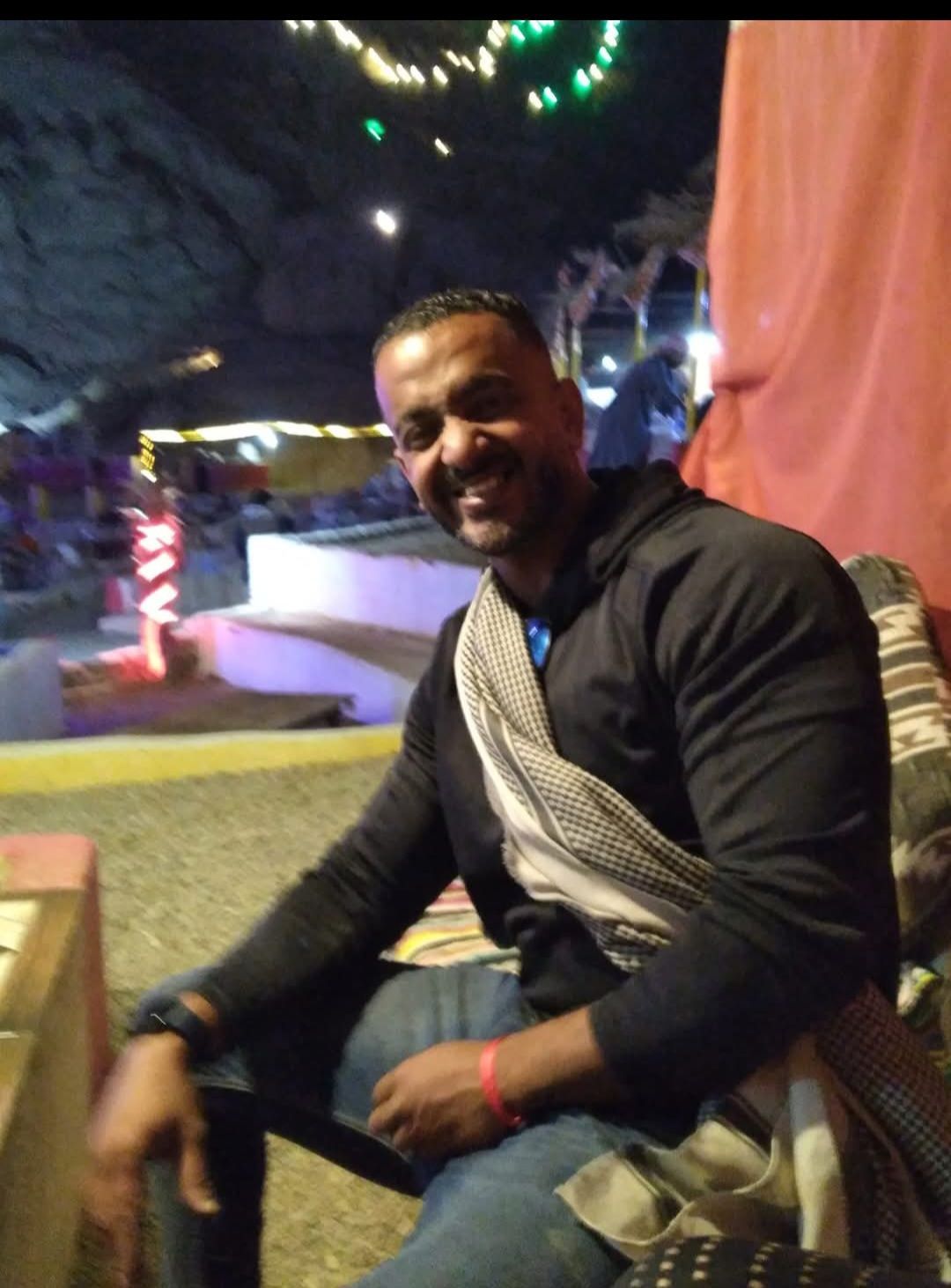 A man in a black jacket is sitting in a chair