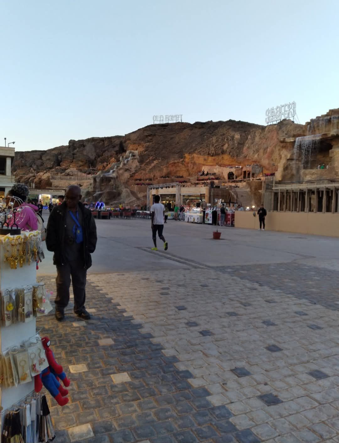A group of people are walking down a sidewalk in front of a building.