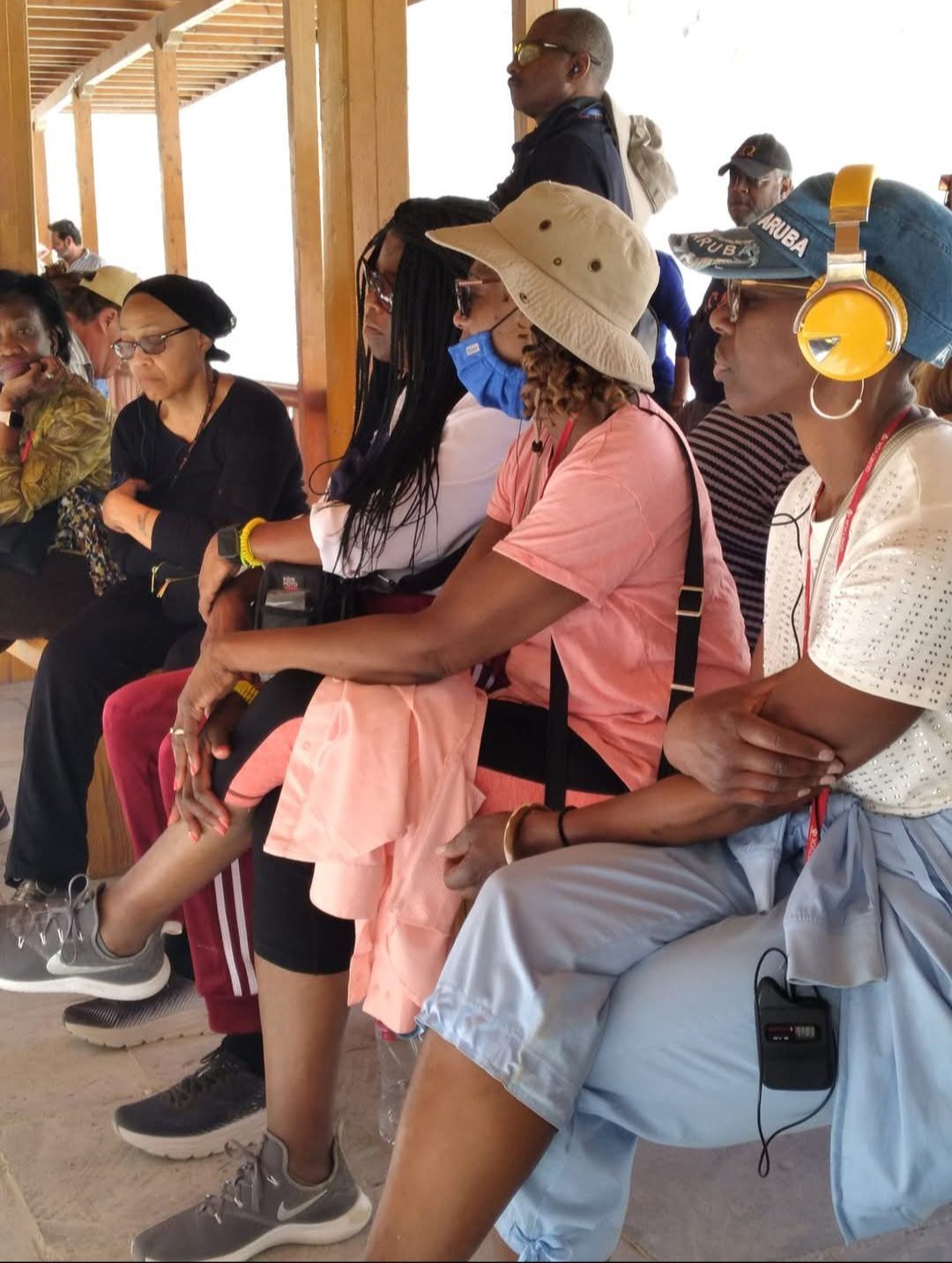 A group of people wearing headphones are sitting on a bench
