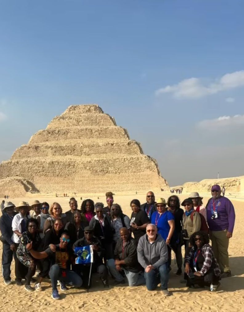 A group of people are posing for a picture in front of a pyramid.