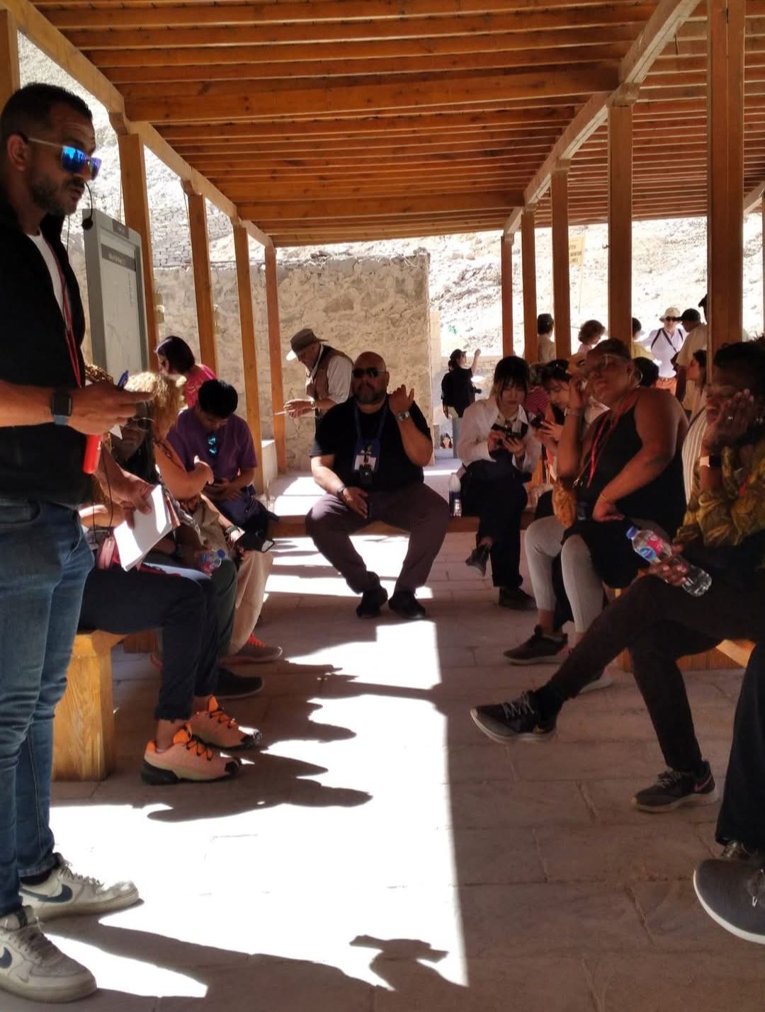 A group of people are sitting under a wooden canopy