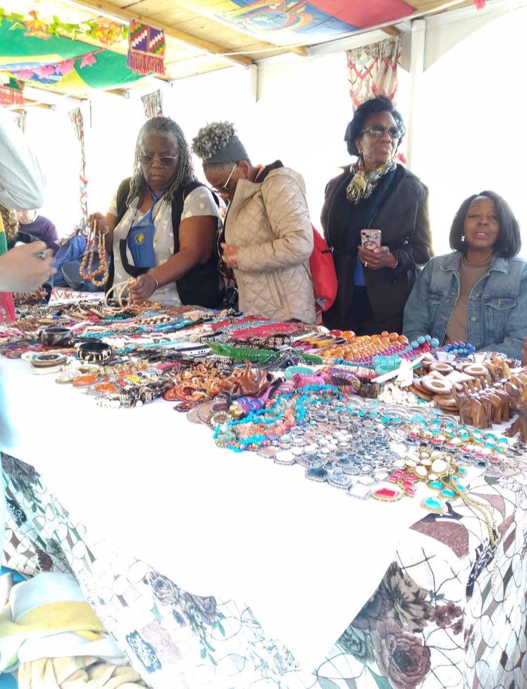 A group of women are standing around a table looking at jewelry.