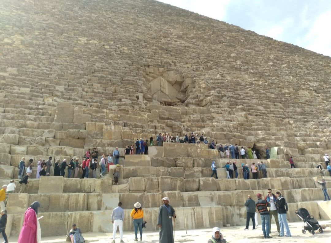 A group of people are standing on the steps of a pyramid.
