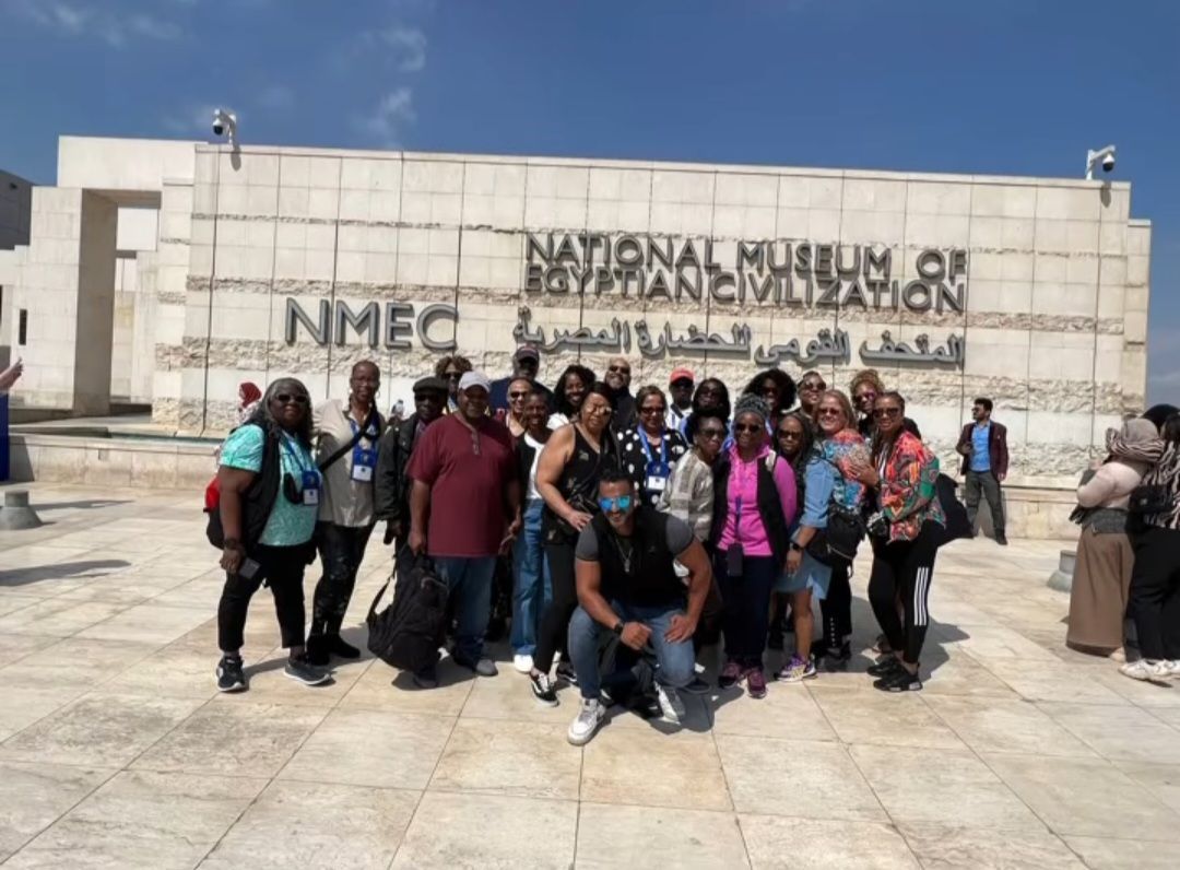 A group of people are posing for a picture in front of a building that says nimec