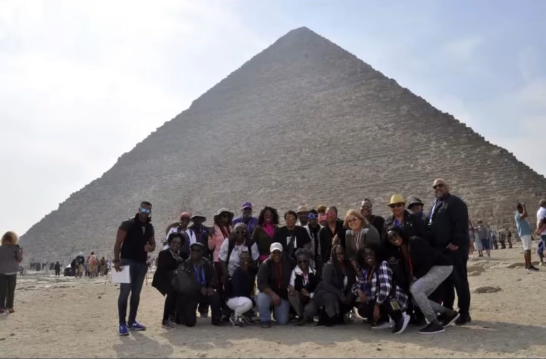 A group of people are posing for a picture in front of a pyramid.