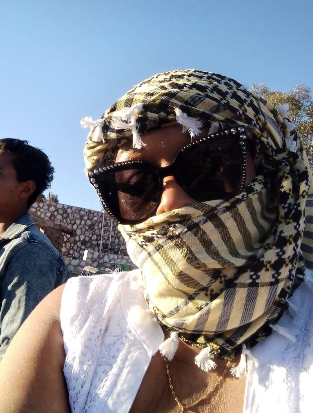 A woman wearing sunglasses and a scarf covering her face