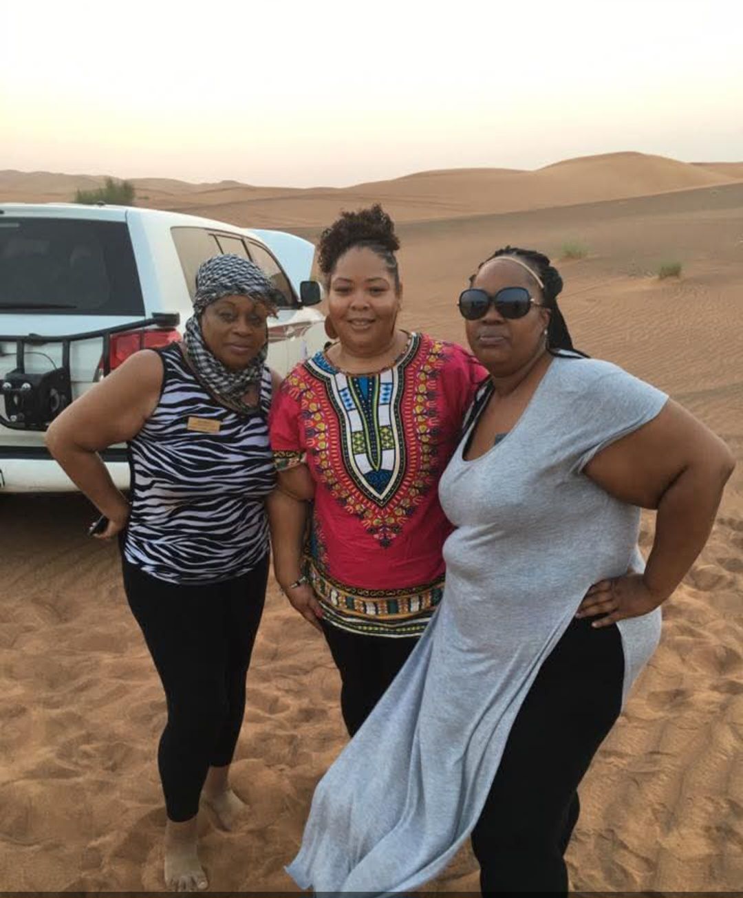 Three women are posing for a picture in the desert