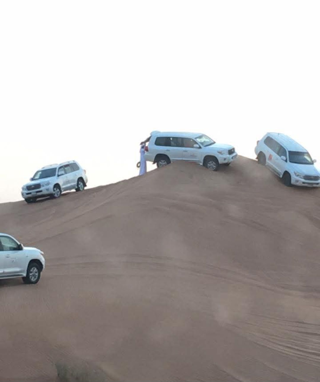 A group of cars are parked on top of a sand dune