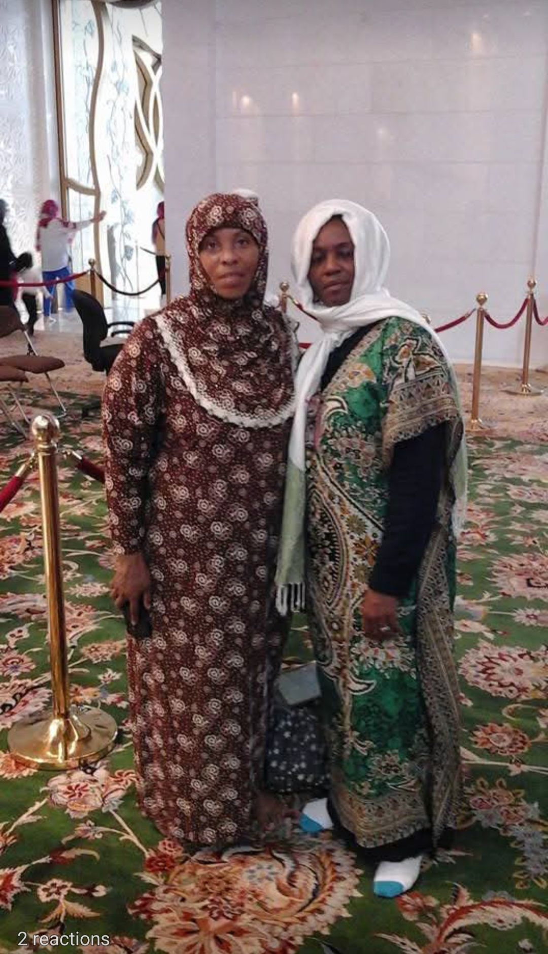 Two women are standing next to each other on a green rug.