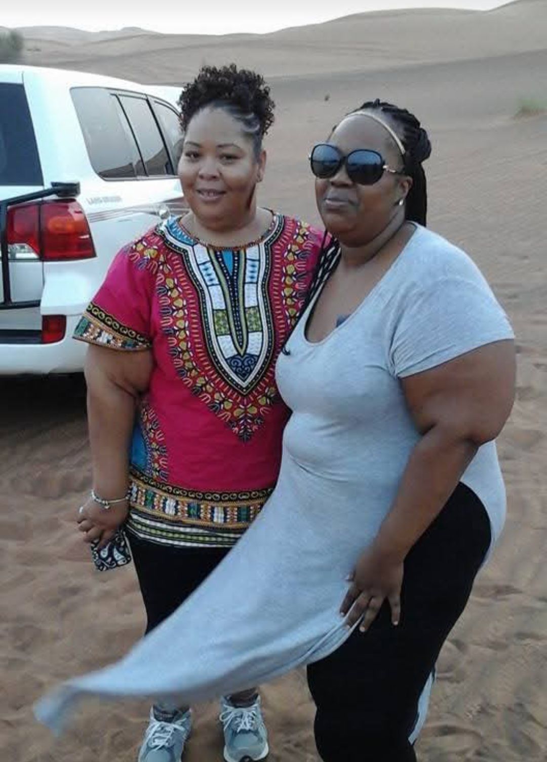 Two women are posing for a picture in the desert